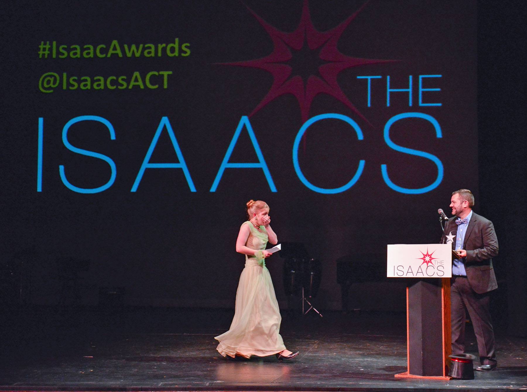 A young female accepts an Isaac Award on stage